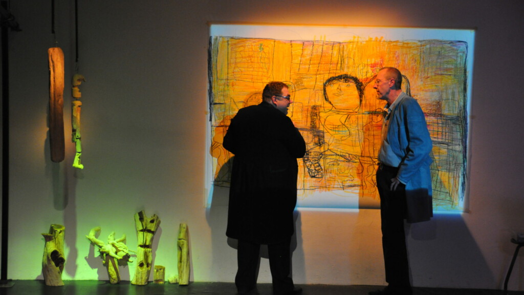 Photo from a performance: Two men in front of a canvas on a stage.