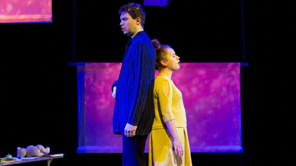 Szene aus einer Aufführung: Ein Mann und eine Frau stehen mit geschlossenen Augen Rücken an Rücken