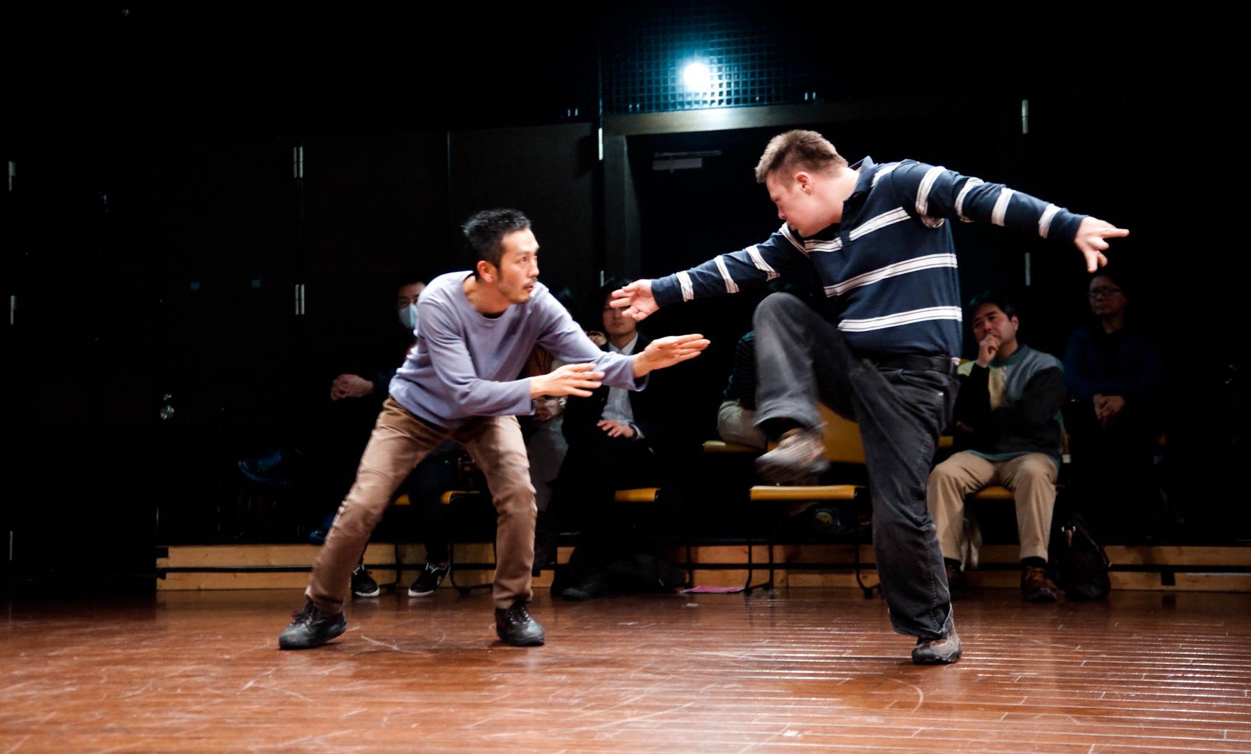 Szenenfoto einer Aufführung: Zwei Männer in Alltagskleidung tanzen.